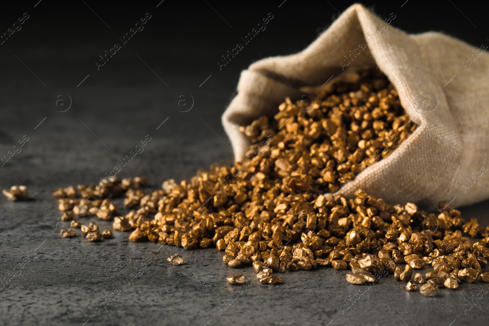 Photo of Overturned sack of gold nuggets on grey table