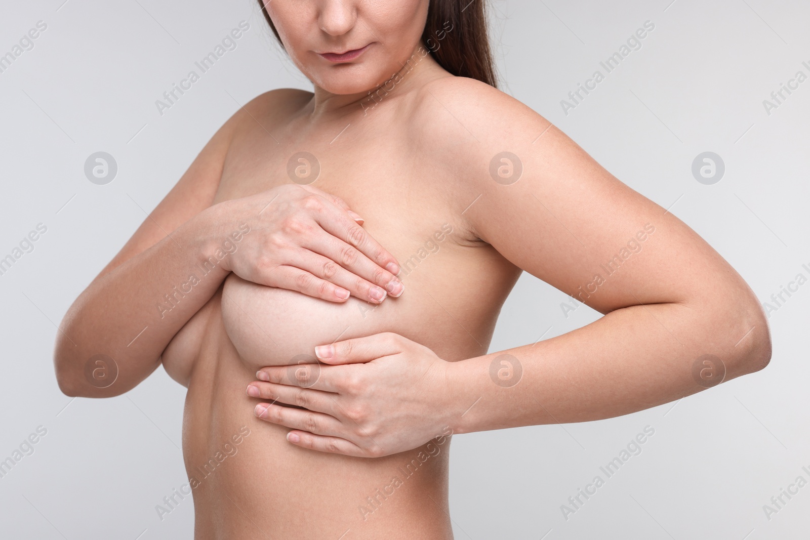 Photo of Mammology. Naked woman doing breast self-examination on light grey background, closeup