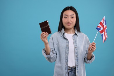 Photo of Immigration to United Kingdom. Woman with passport and flag on light blue background, space for text