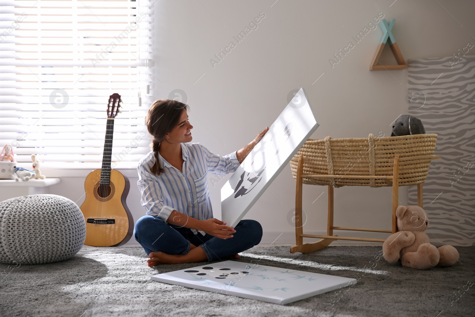 Photo of Decorator with pictures on floor in baby room. Interior design