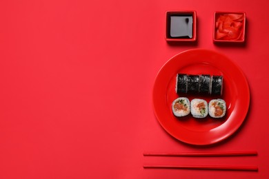 Photo of Tasty sushi rolls, soy sauce and ginger on red background, flat lay. Space for text