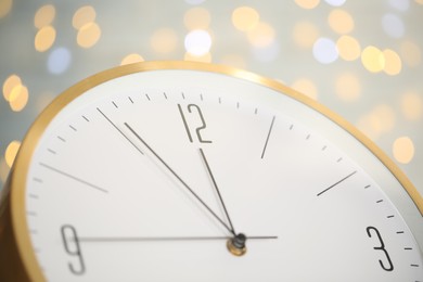 Photo of Clock showing five minutes until midnight on blurred background, closeup. New Year countdown