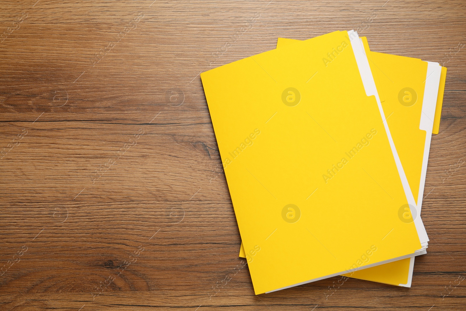 Photo of Yellow files with documents on wooden table, top view. Space for text