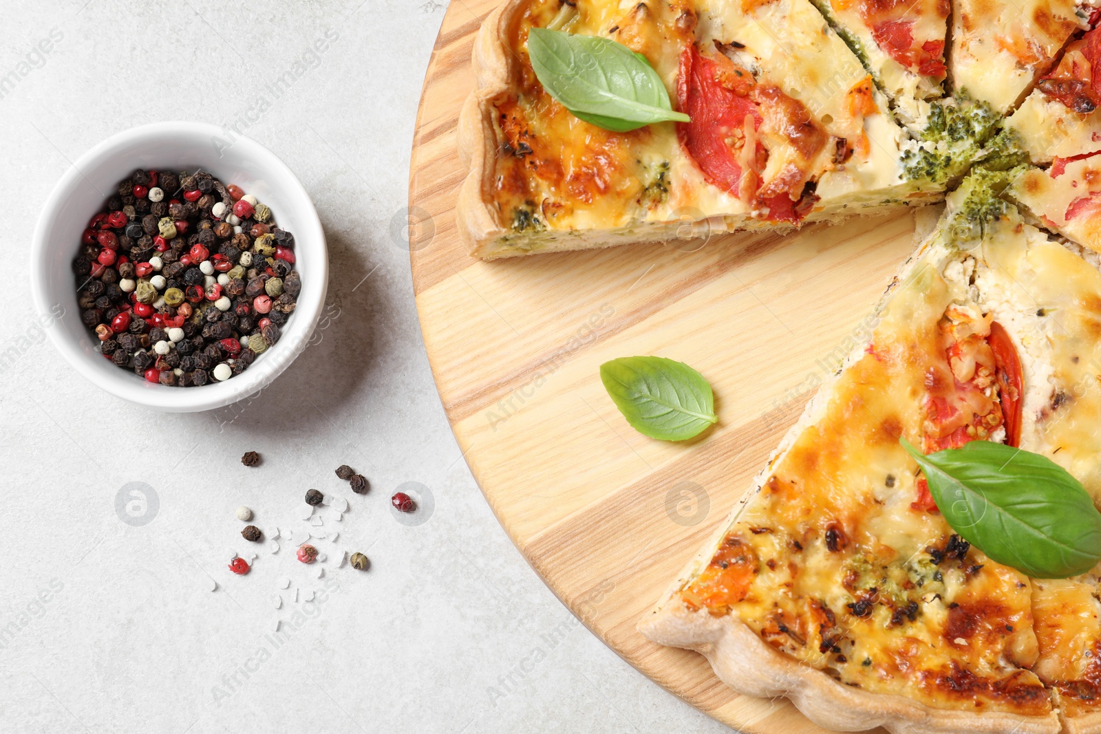 Photo of Tasty quiche with tomatoes, basil and cheese served on light textured table, flat lay