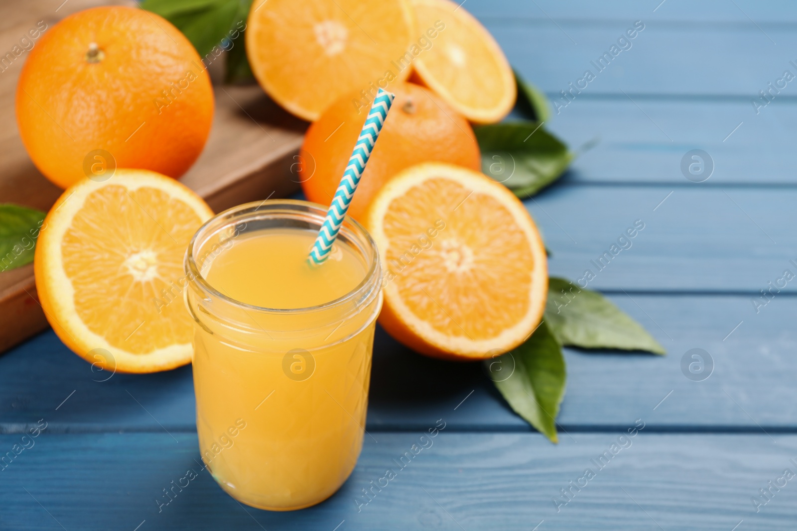 Photo of Delicious orange juice and fresh fruits on blue wooden table. Space for text