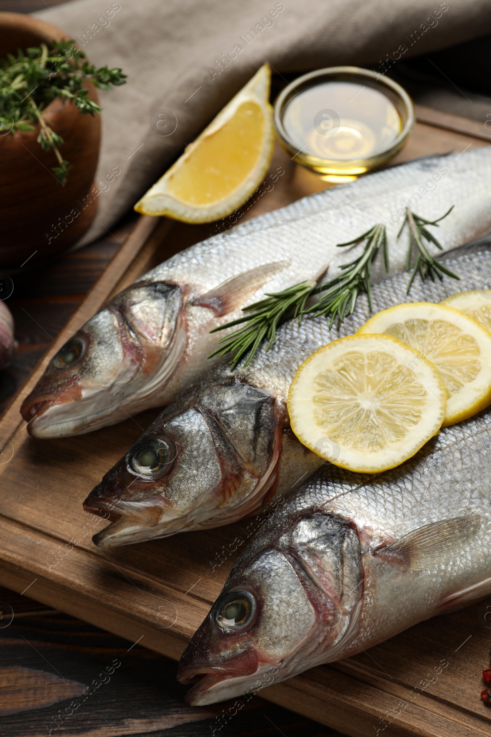 Photo of Sea bass fish and ingredients on wooden table, closeup