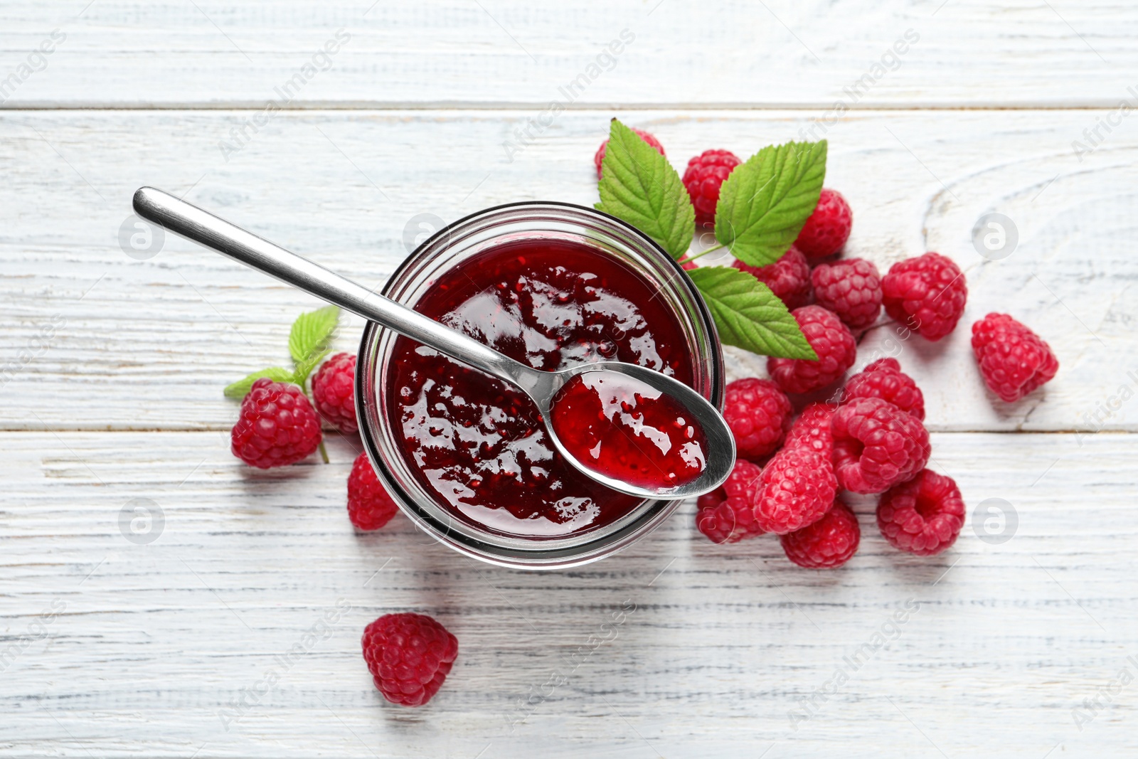 Image of Sweet raspberry jam and fresh berries on white wooden table, flat lay