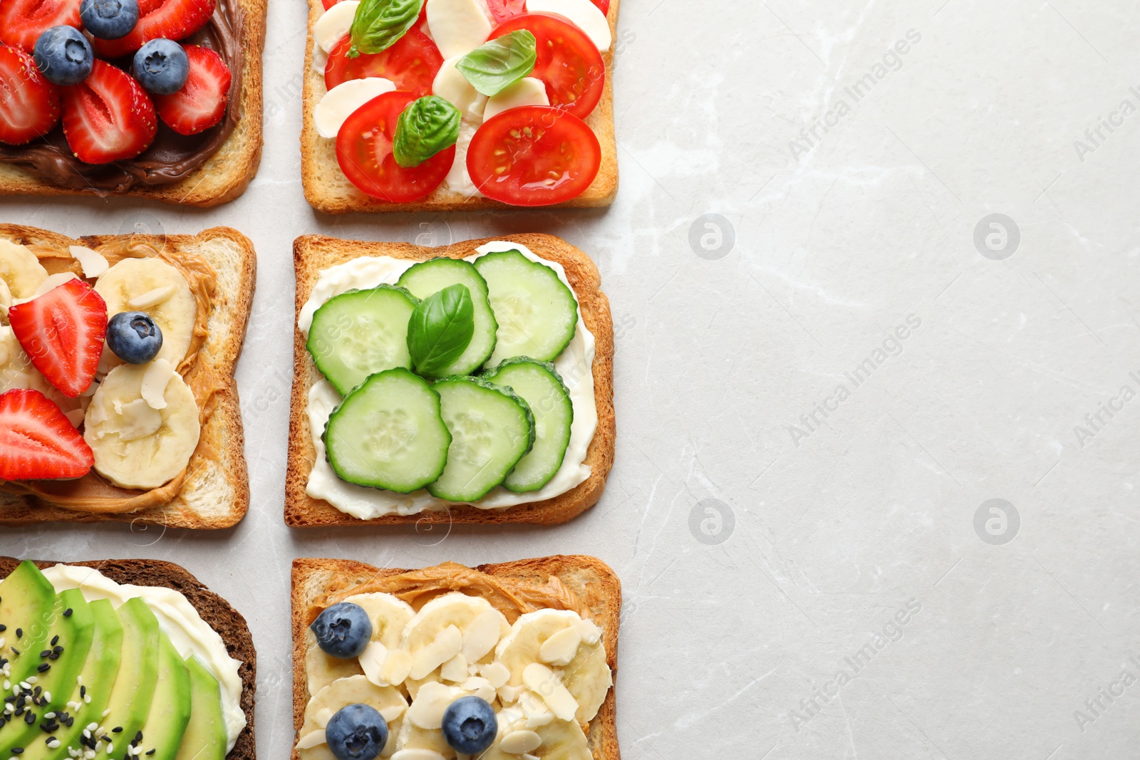 Photo of Tasty toast bread with fruits, berries and vegetables on light background