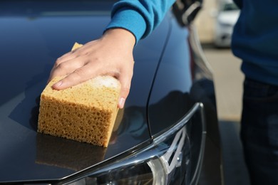 Photo of Man washing car hood with sponge, closeup