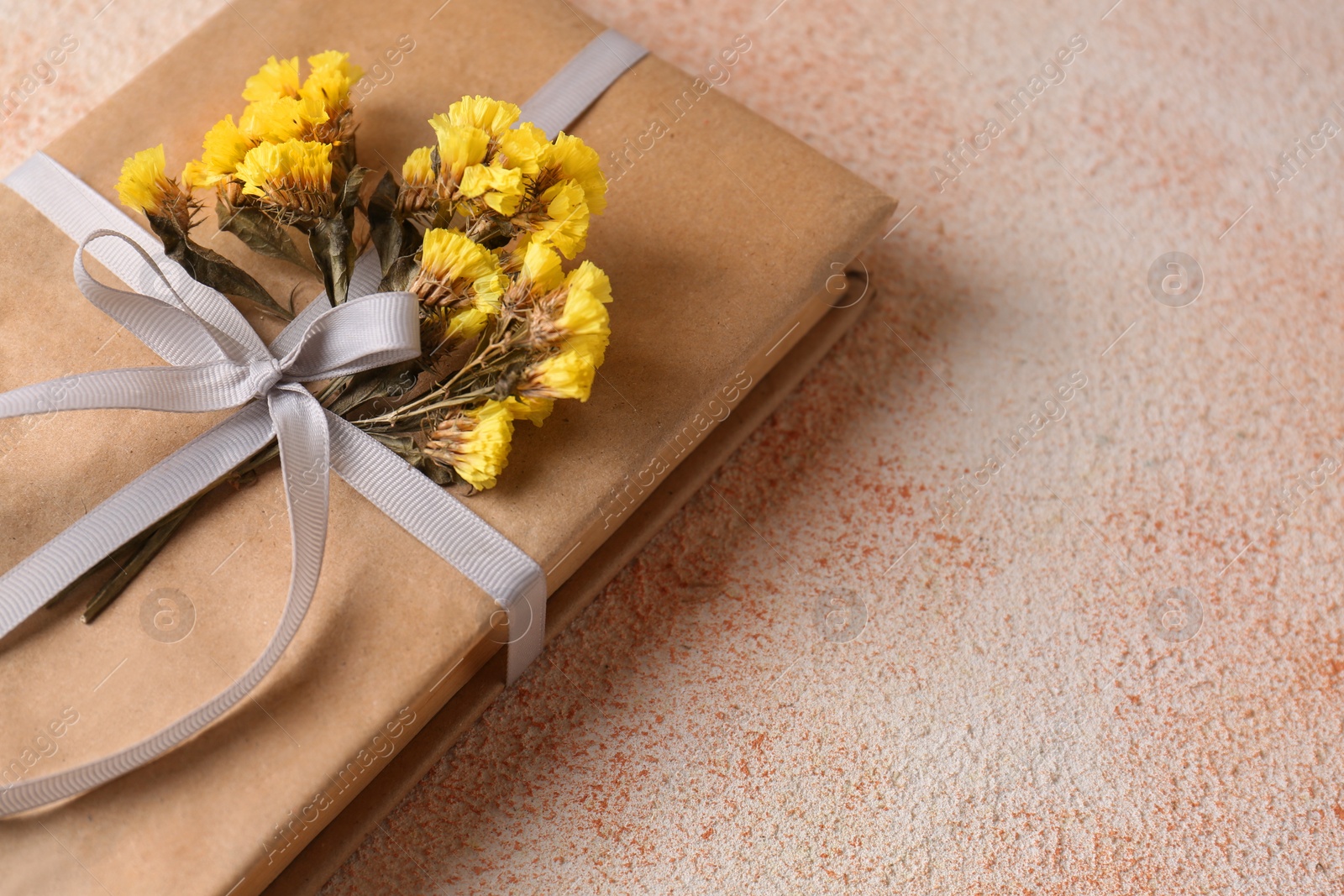 Photo of Book decorated with flowers on beige textured table, closeup