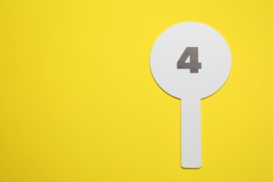 Auction paddle with number 4 on yellow background, top view. Space for text