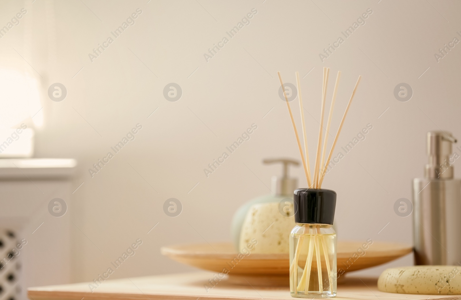 Photo of Aromatic reed air freshener and toiletries on table indoors