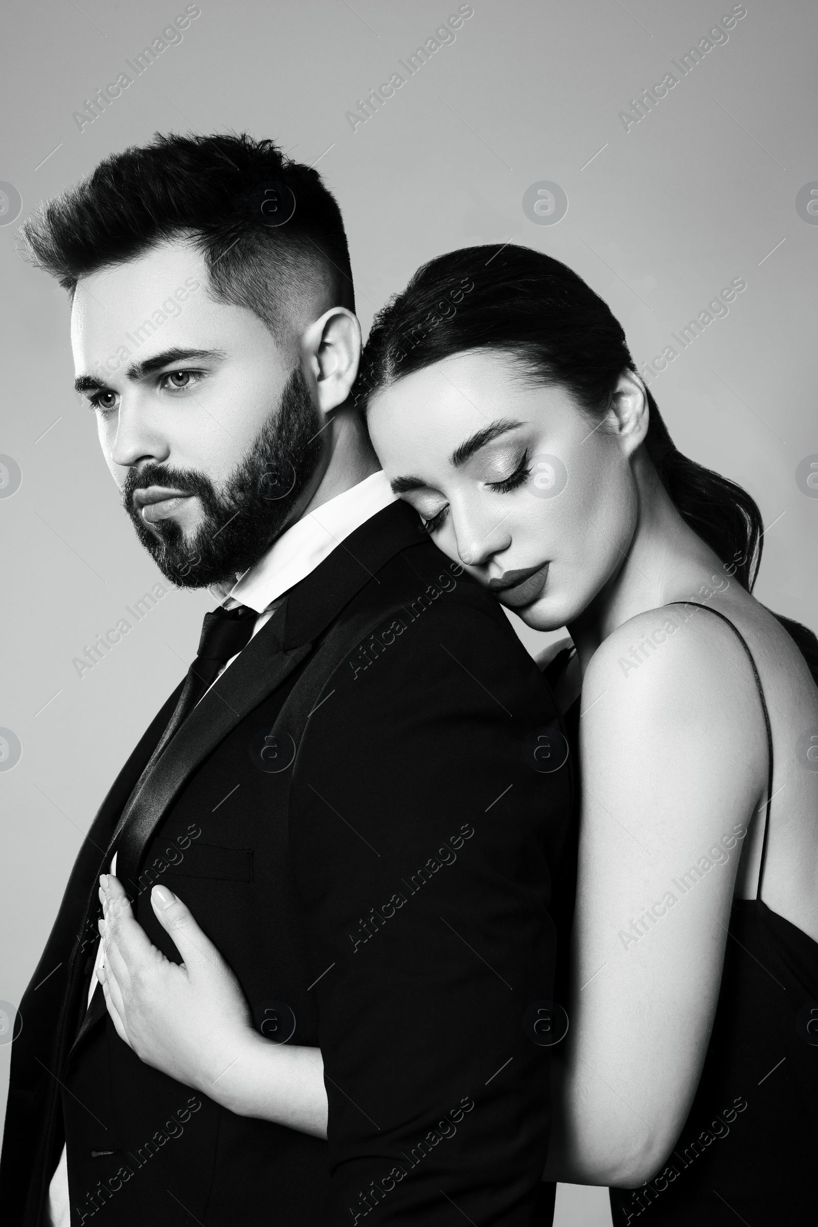 Image of Handsome bearded man with sexy lady on grey background. Black and white effect