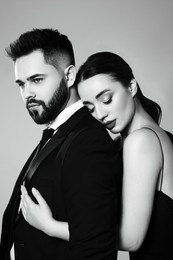 Image of Handsome bearded man with sexy lady on grey background. Black and white effect