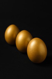 Photo of Three shiny golden eggs on black background