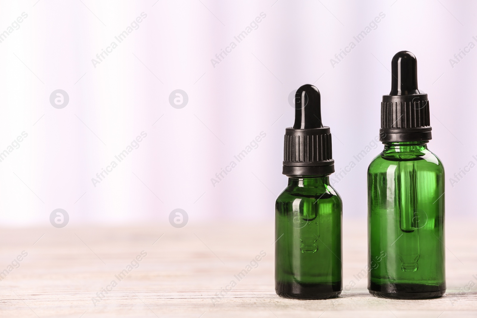 Photo of Bottles of essential oils on table against light background, space for text. Cosmetic products