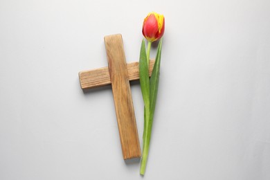 Easter - celebration of Jesus resurrection. Wooden cross and tulip on light background, top view