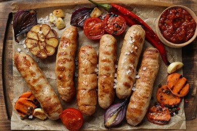 Photo of Tasty grilled sausages and products on wooden board, flat lay