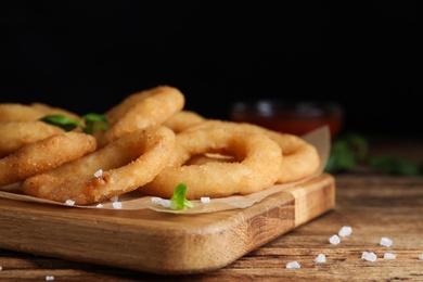 Photo of Delicious onion rings on wooden table, closeup