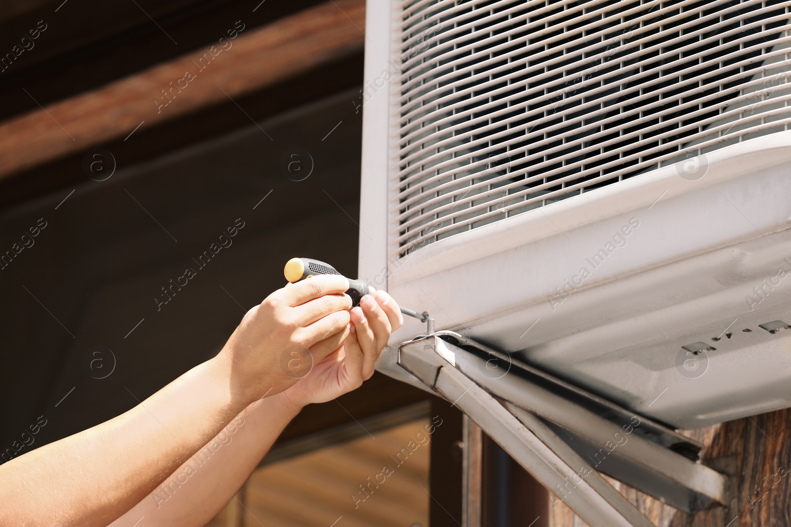 Photo of Professional technician maintaining modern air conditioner outdoors, closeup