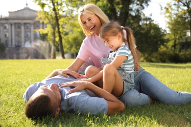 Happy parents with their child having fun on green grass. Spending time in nature