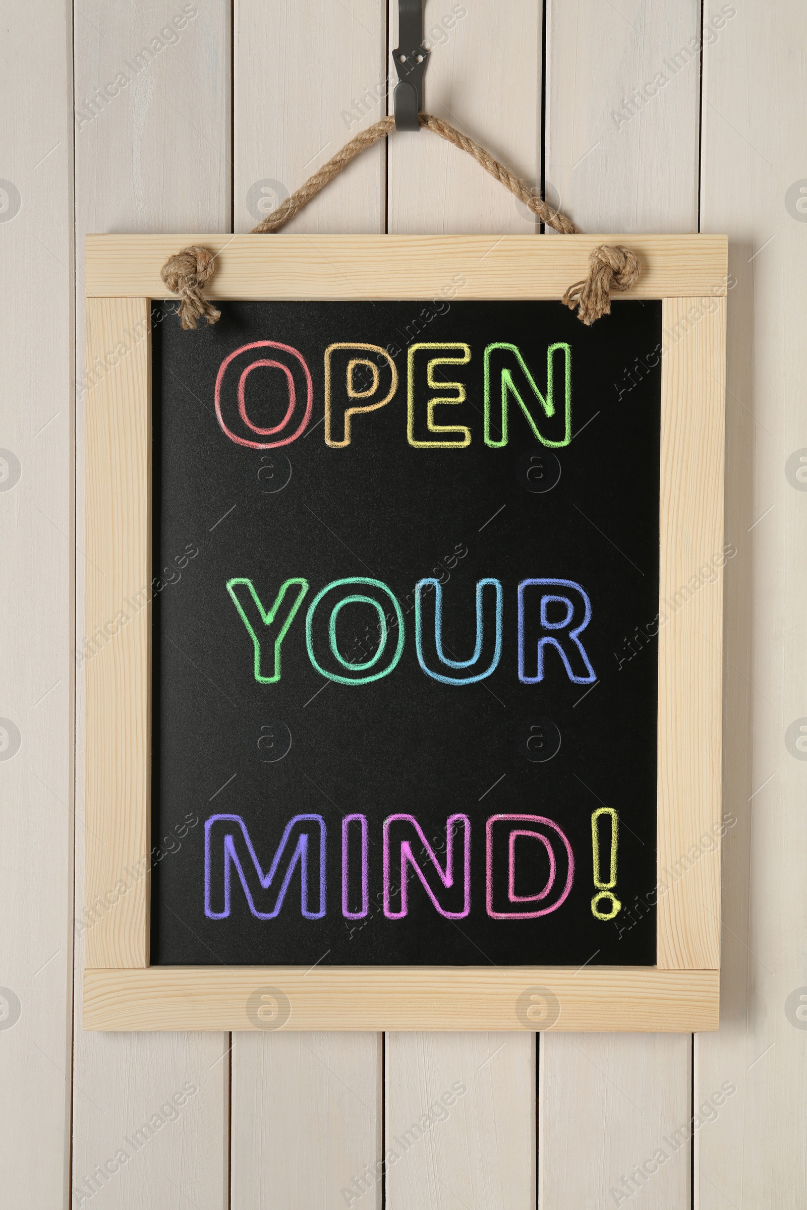 Image of Small chalkboard with motivational quote Open your mind hanging on white wooden wall