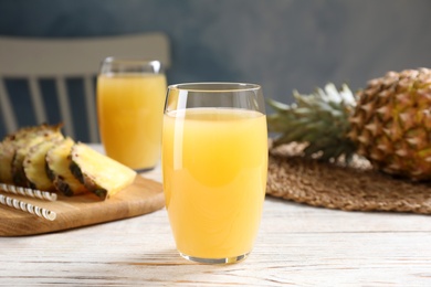 Photo of Delicious pineapple juice in glass on white wooden table