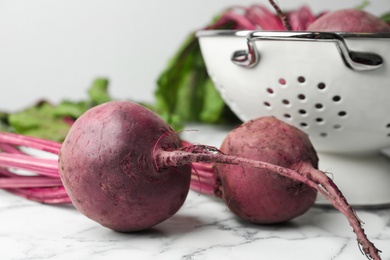Photo of Raw ripe beets on white marble table, closeup