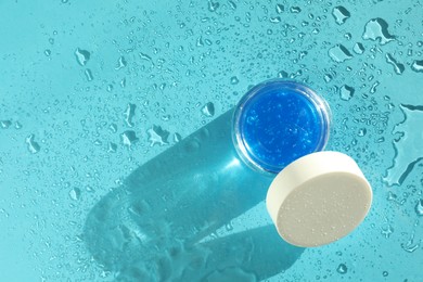 Photo of Open jar of cosmetic product on wet turquoise background, top view. Space for text