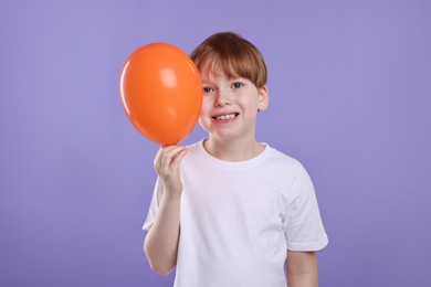 Photo of Boy with orange balloon on violet background