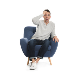 Emotional young man sitting in armchair on white background