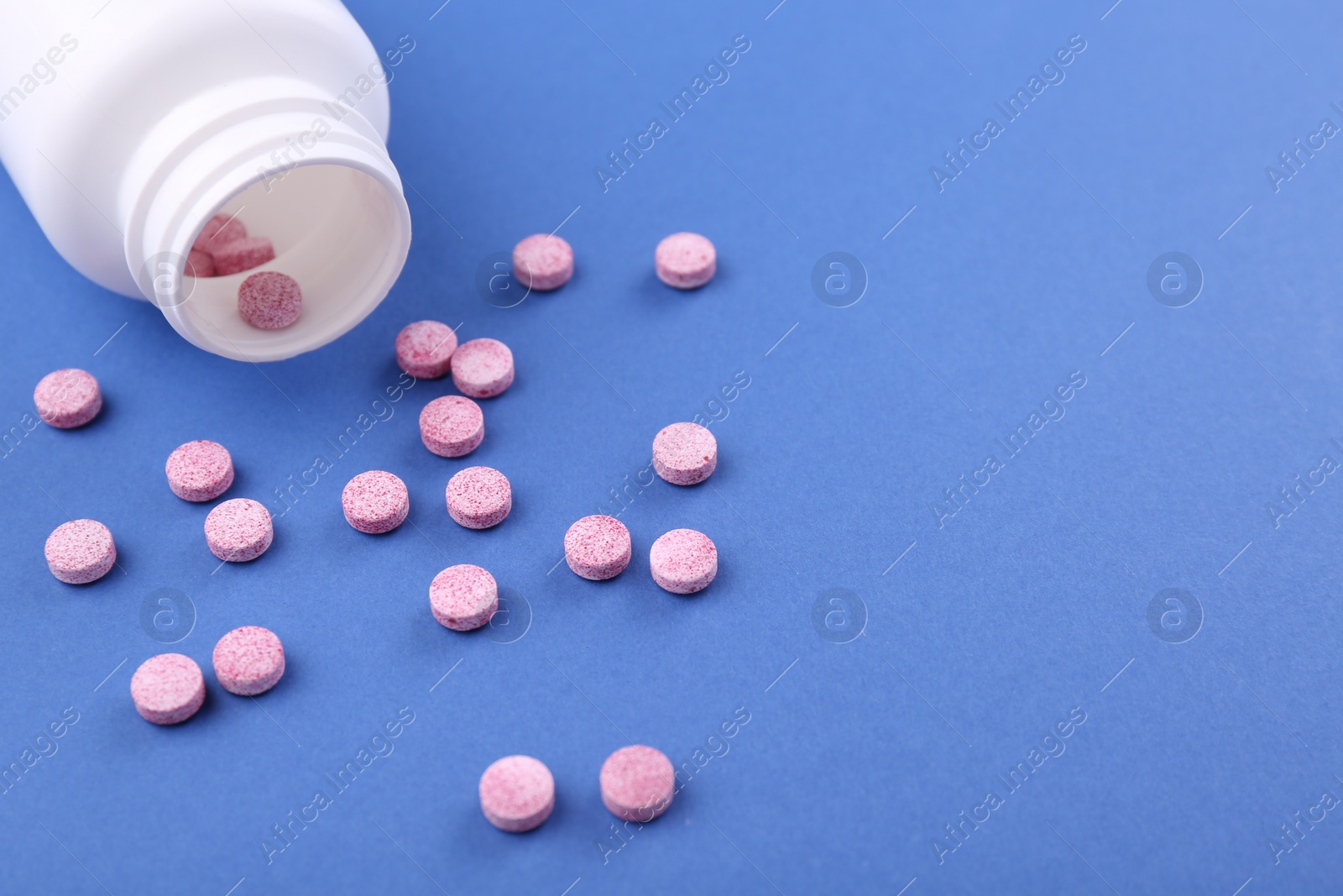 Photo of Bottle and vitamin pills on blue background, closeup. Space for text