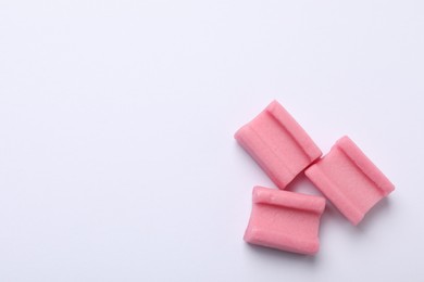 Photo of Tasty pink chewing gums on white background, flat lay. Space for text