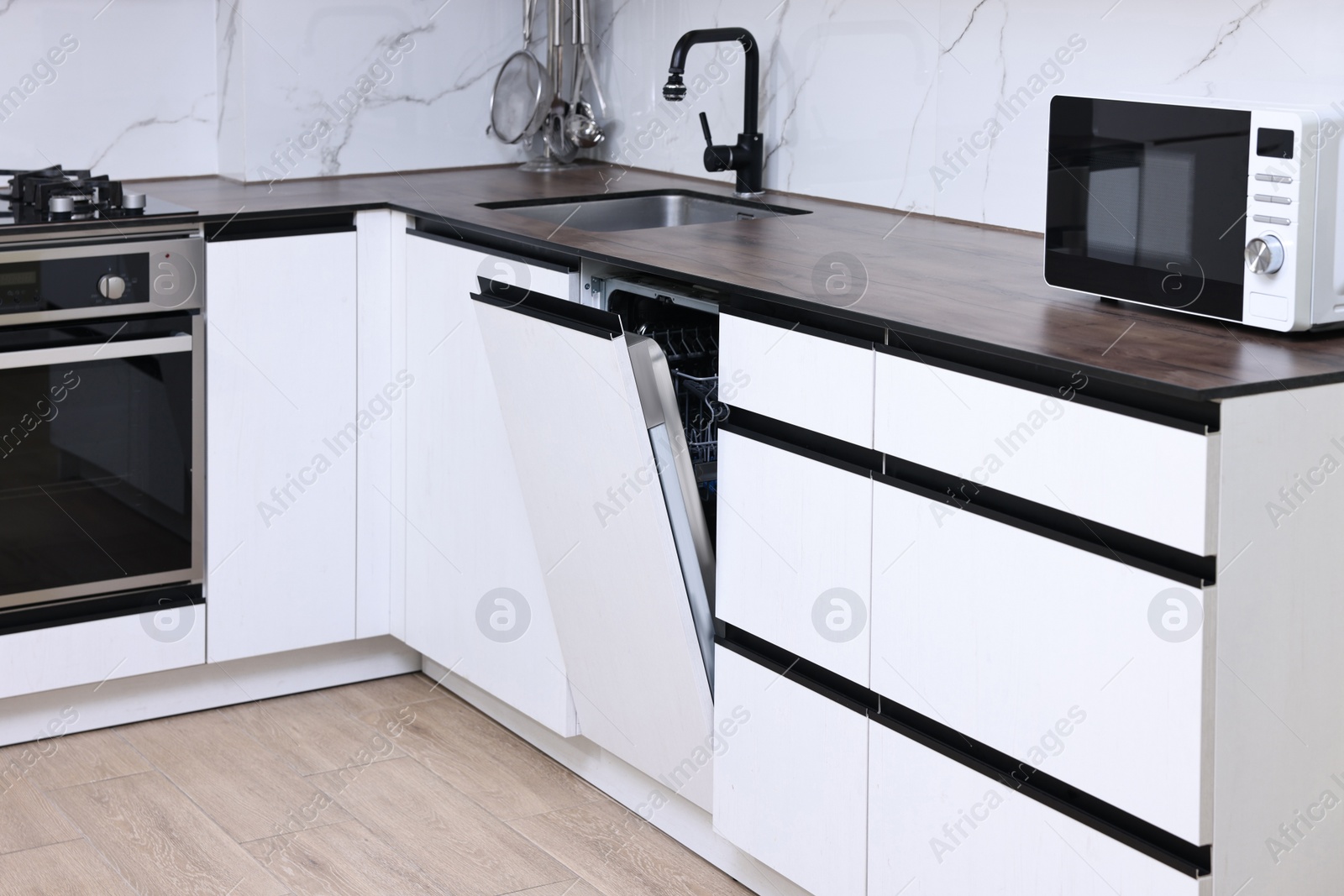 Photo of Built-in dishwasher with open door in kitchen