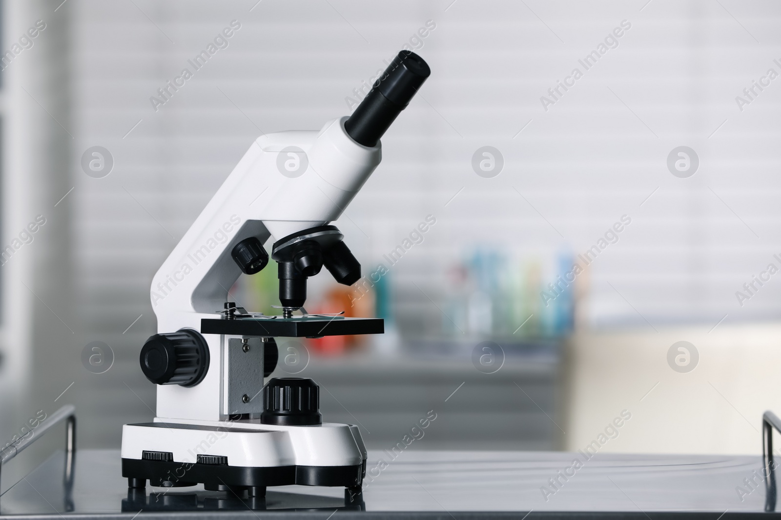 Photo of Modern medical microscope on metal table in laboratory, space for text