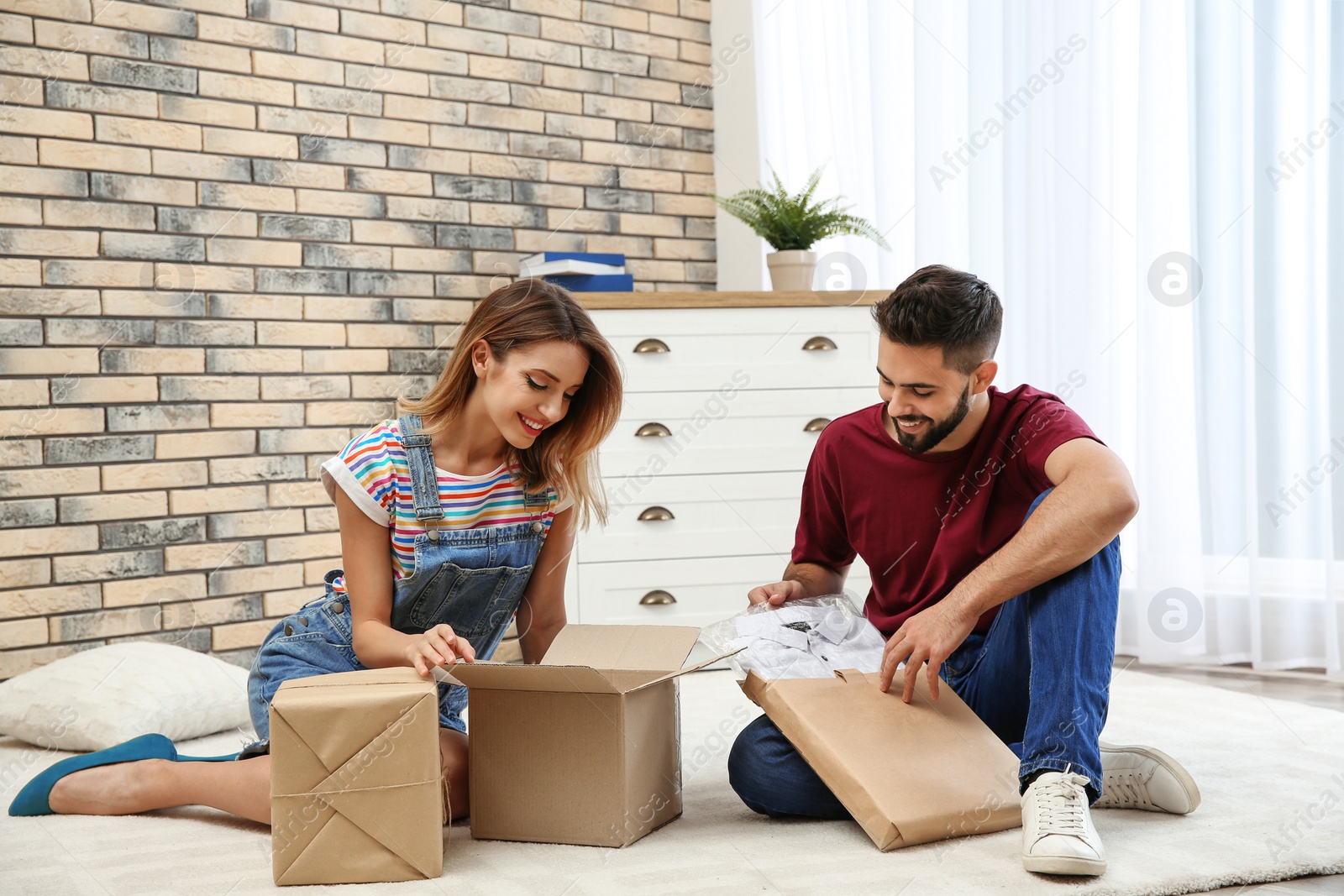 Photo of Young couple opening parcels on floor at home