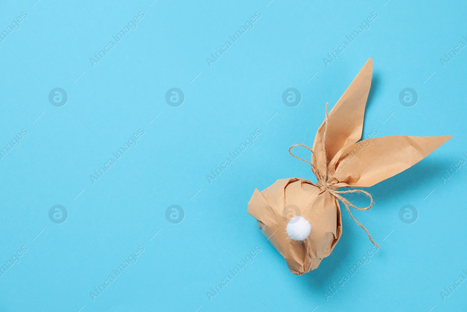 Photo of Creative Easter bunny gift bag on color background, top view with space for text