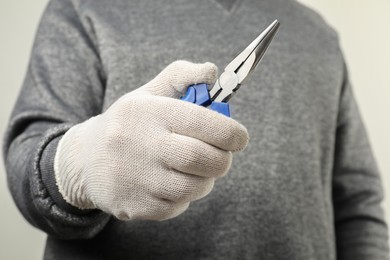 Photo of Man with needle nose pliers on light background, closeup. Space for text