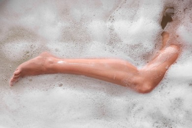 Photo of Woman taking bath in tub with foam, top view