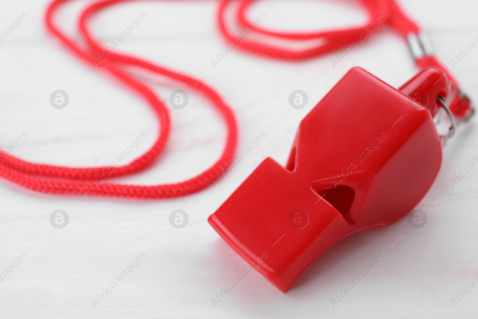 Photo of One red whistle with cord on white wooden table, closeup. Space for text