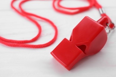 One red whistle with cord on white wooden table, closeup. Space for text