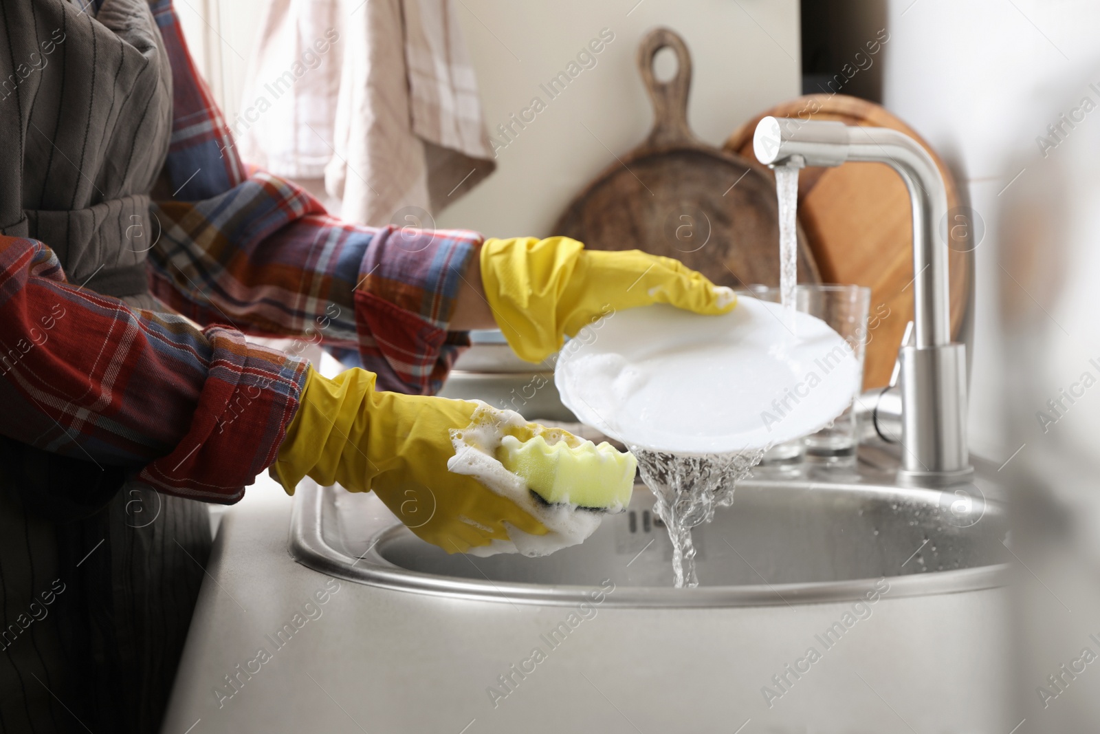 Photo of Woman washing plate in kitchen sink, closeup