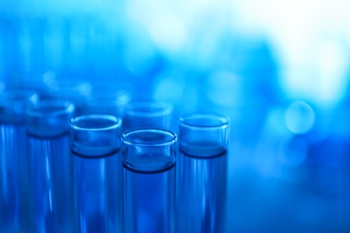 Photo of Test tubes with blue liquid on blurred background, closeup. Laboratory analysis