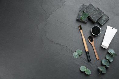 Photo of Flat lay composition with bamboo toothbrush on black stone table. Space for text