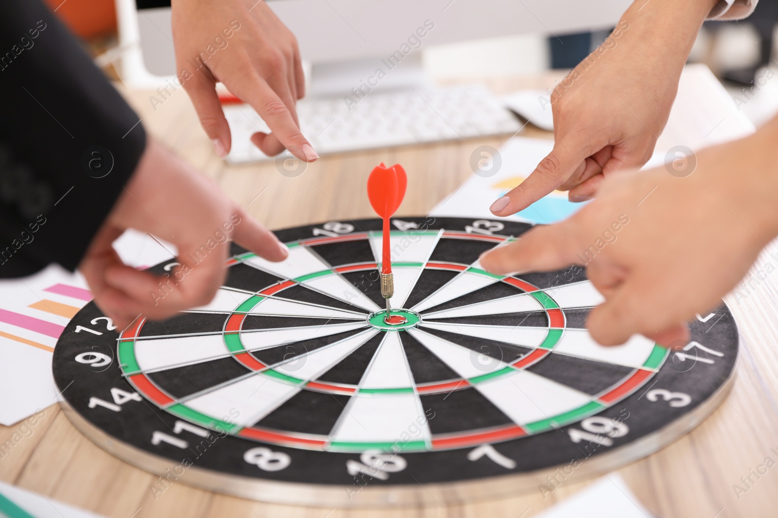 Photo of Employees pointing on dart board lying on table, closeup