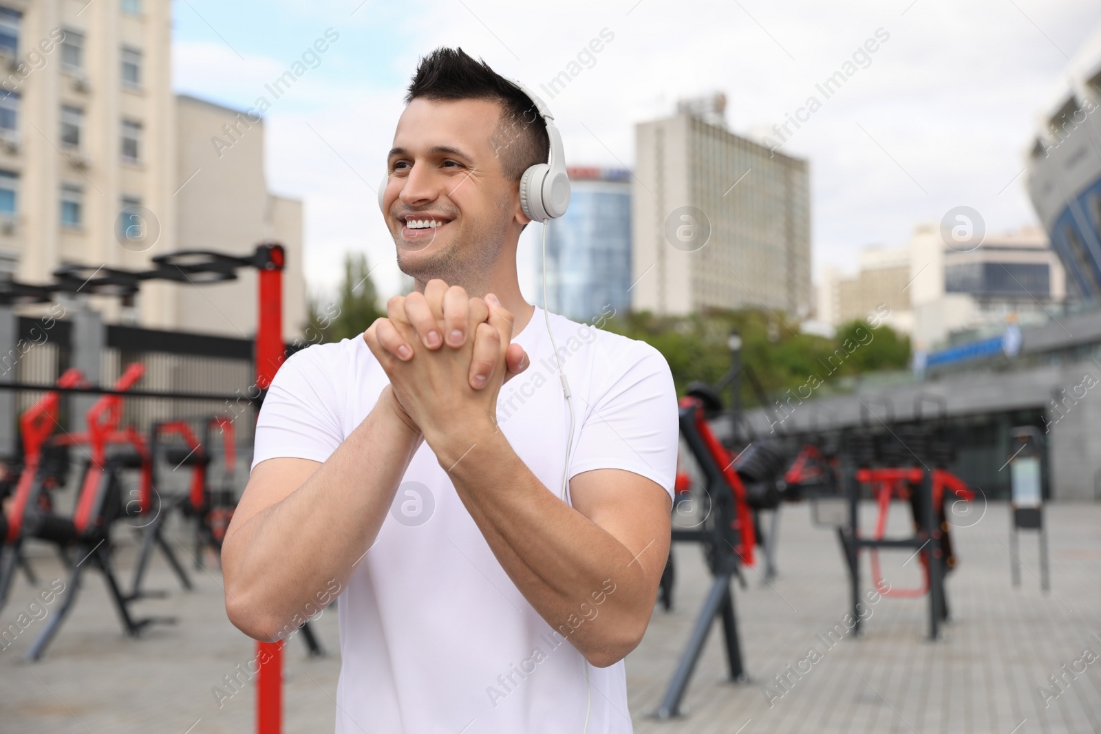 Photo of Man with headphones doing fitness exercise in morning near outdoor gym