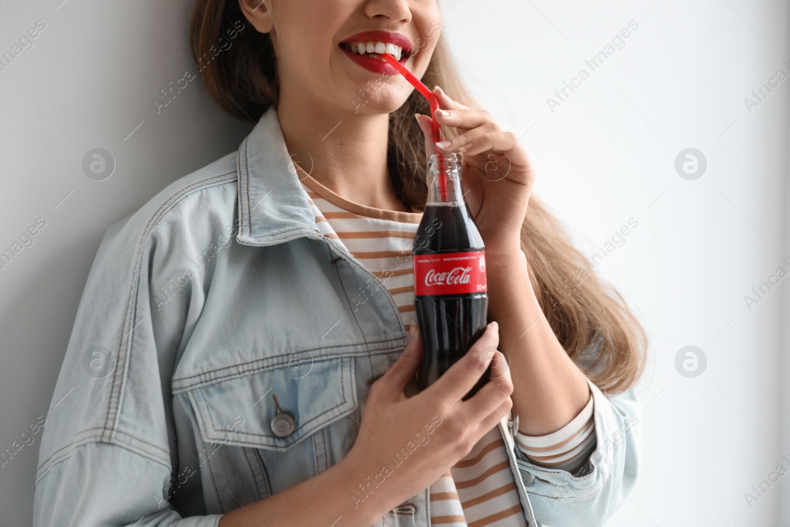 Photo of MYKOLAIV, UKRAINE - NOVEMBER 28, 2018: Young woman with bottle of Coca-Cola on white background