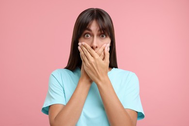 Photo of Embarrassed woman covering mouth with hands on pink background
