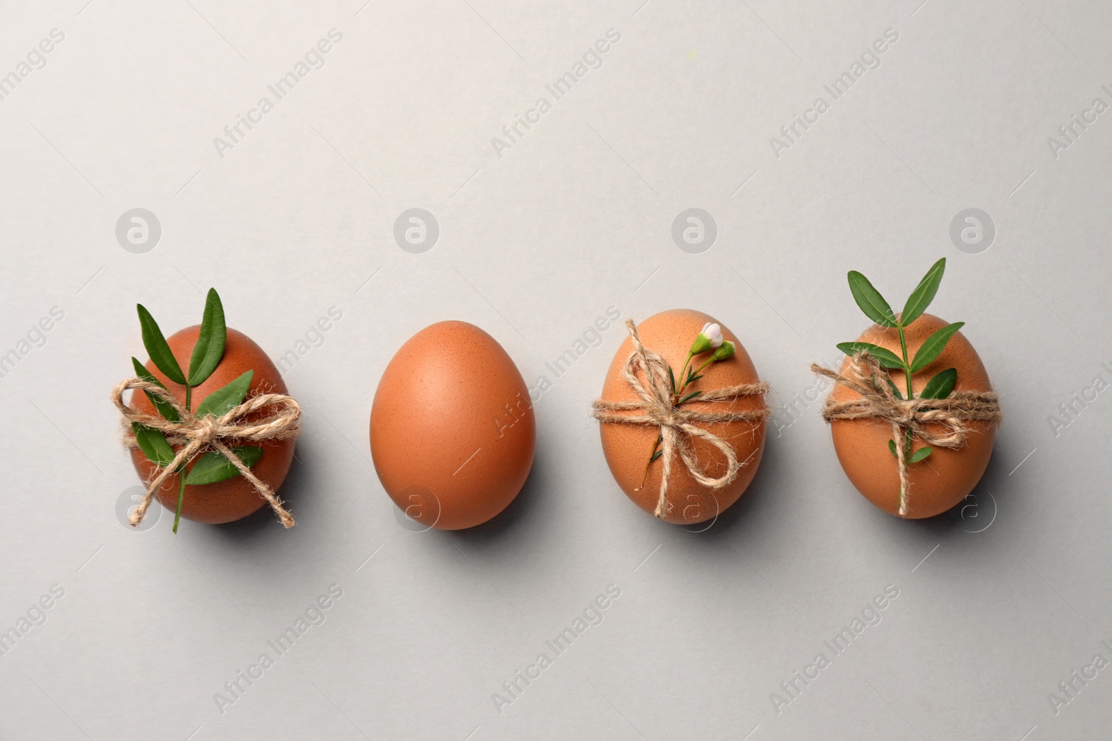 Photo of Chicken eggs and natural decor on light grey background, flat lay. Happy Easter