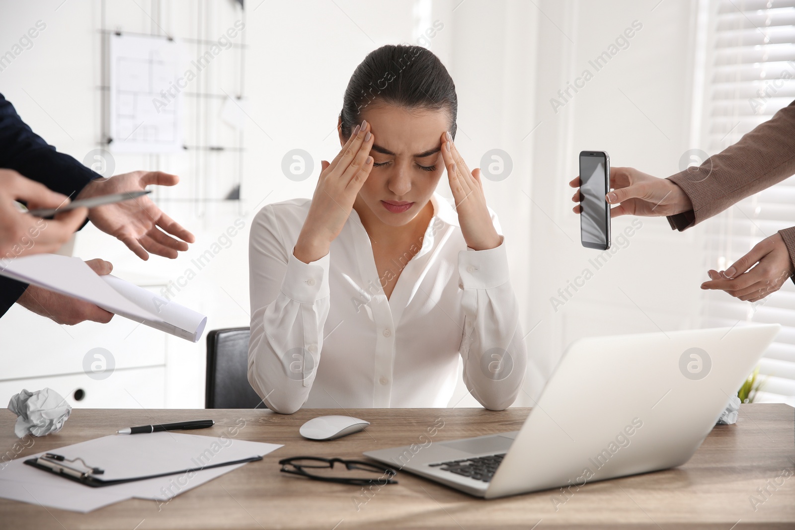 Photo of Stressed and tired young woman surrounded by colleagues at workplace, closeup